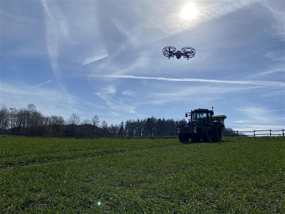 Eine Drohne fliegt über einem Traktor.